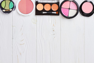 Set of multicolored eyeshadows, copy space. Decorative cosmetics on white wooden background, space for text.