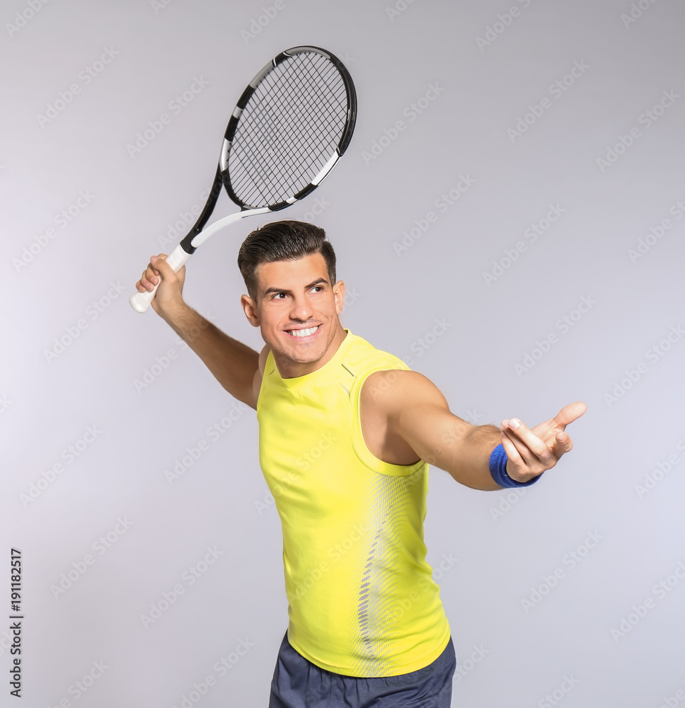 Canvas Prints Portrait of handsome man playing tennis against grey background