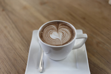 Top view cup of hot coffee latte art heart-shaped wooden floor.