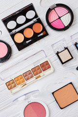 Pink and brown eyeshadows palette. Set of decorative cosmetics for eyes make up on white wooden background, top view. Female brand cosmetics.