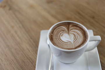 Top view cup of hot coffee latte art heart-shaped wooden floor.