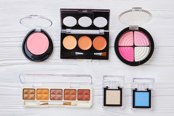 Decorative cosmetics set, top view. Collection of make u products with multicolored eyeshadows and blushers, white wooden background. Make up artist new collection of eyeshadows.