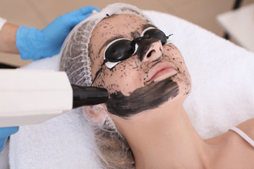 Young woman undergoing carbon peeling procedure in salon