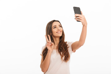 Smiling brunette woman in t-shirt making selfie on smartphone