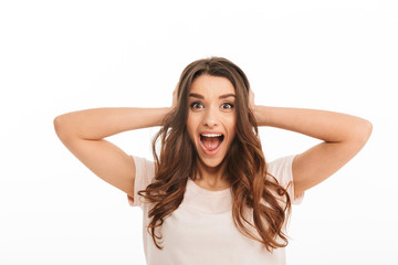 Fototapeta premium Surprised happy brunette woman in t-shirt screaming and covering ears