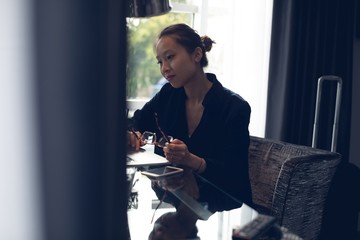 Thoughtful woman sitting with spectacles at table