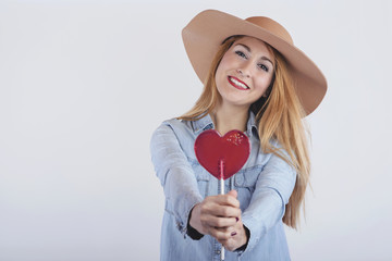 chica sonriente con piruleta con forma de corazón