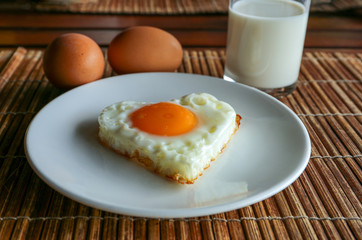 Fried egg on a white dish and a glass of fresh milk
