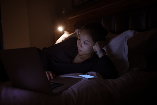 Beautiful woman using laptop on bed