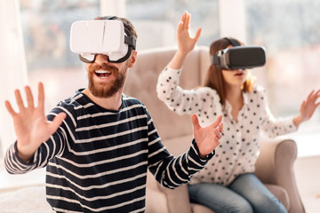 Virtual journey. Gay appealing vigorous man laughing while resting and wearing VR headset