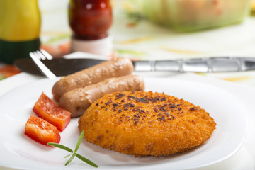Chicken cordon Bleu on plate with two sausages
