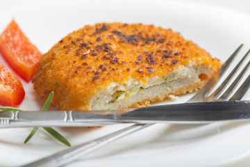 Chicken cordon Bleu on plate with fork and knife