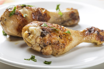 Closeup of two grilled chicken drumsticks with parsley