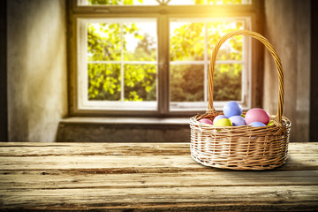Easter eggs on wooden table in basket and background of window of spring. 