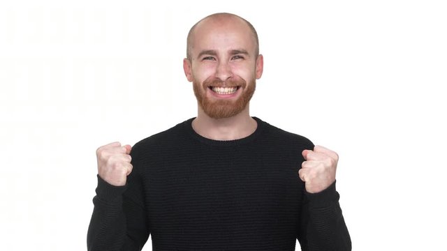 Portrait of young man being ecstatic about reaching goals, clenching fists in pleasure like winner or successful person over white background. Concept of emotions