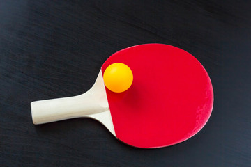 table tennis or ping pong racket and ball on a black background