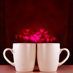 Two cups on dark background with bokeh. The concept of Valentine's Day