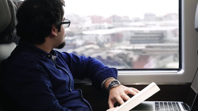 A man reads a book while traveling on a train