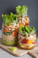vegan couscous and pasta salad in mason jars with vegetables beans