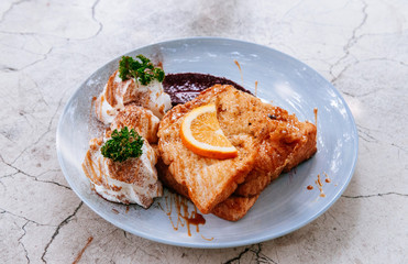 Beautiful French toast dish with orange honey sauce, strawberry jam, on white marble table