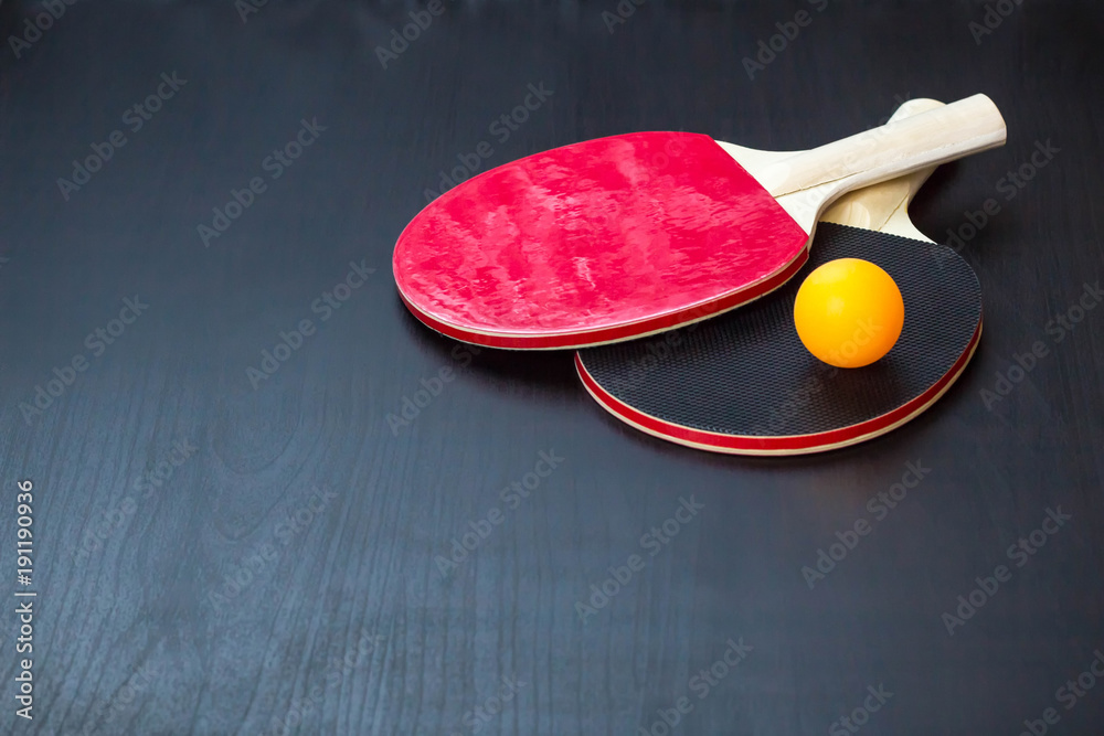 Wall mural two table tennis or ping pong rackets and ball on a black background