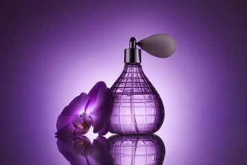 perfume bottle with fresh orchid flower on purple background
