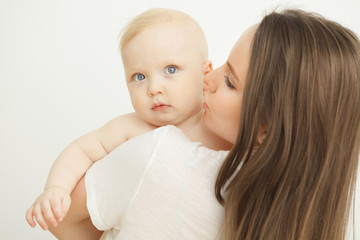Mother kisses child in cheek, baby rests on mom shoulder