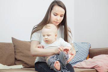 Mother holds on hands her favourite child going to change him clothes.