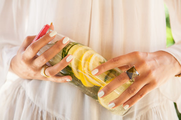 Jus detox avec du citron et du concombre dans les mains d'une femme