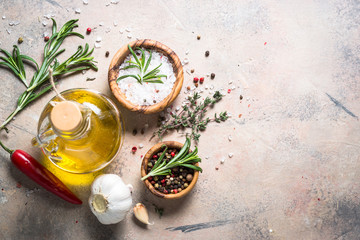 Spices and herbs background - olive oil rosemary on stone table.