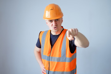 angry builder worker in orange protecting cask and working clothes pointing with finger