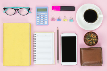 Mobile and old book and notebook pencil glasses black coffee white cup and paper clip cactus on pink background flatlay pastel style.