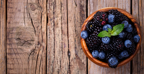 Blackberry and Blueberry with Mint. Fresh Berry in a wooden bowl on a wooden Vintage Background.Food or Healthy diet concept.Vegetarian.Copy space for Text.selective focus