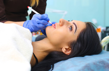 Obraz na płótnie Canvas Cosmetologist making permanent makeup on woman's face