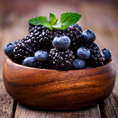Blackberry and Blueberry with Mint. Fresh Berry in a wooden bowl on a wooden Vintage Background.Food or Healthy diet concept.Vegetarian.Copy space for Text.selective focus