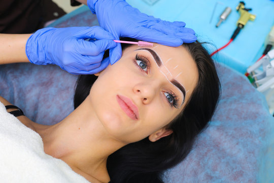 Young beautiful woman making permanent makeup in cosmetology salon.