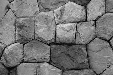 stone wall is built from different size of rocks. background and wallpaper. black and white photo.
