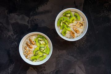 Oatmeal porridge with kiwi fruit and walnuts top view