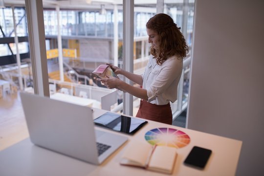 Female Graphic Designer Looking At Color Swatch Book