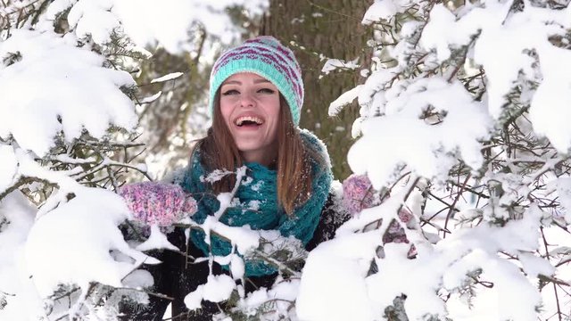 Young girl having fun near snowy christmas tree branches in the park, outdoor sunny day