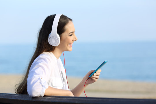 Profile of a girl listening to music on the beach