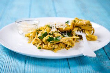 Fettuccine Pasta with sauce. Hot dish with Parmesan cheese, decorated with green parsley on a blue background.Copy space for Text.selective focus.