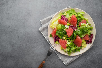 Fresh mix salad with lettuce, green arugula and sliced grapefruit in a plate