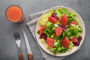 Fresh mix salad with lettuce, green arugula and sliced grapefruit in a plate