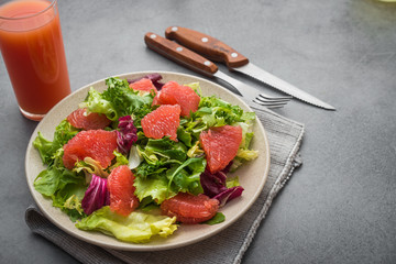 Fresh mix salad with lettuce, green arugula and sliced grapefruit in a plate