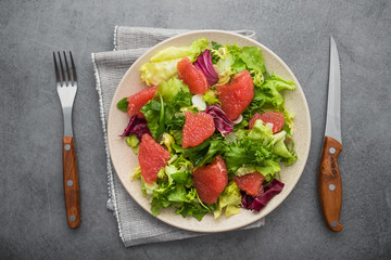 Fresh mix salad with lettuce, green arugula and sliced grapefruit in a plate