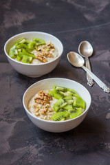 Oatmeal with kiwi fruit and walnuts. Two bowls porridge