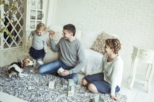 happy family playing with a pet dog in the spacious living room