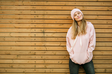 cool young woman in pink hoodie on wooden background
