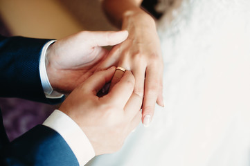 the groom puts on an engagement golden ring on the finger of the bride during wedding ceremony....